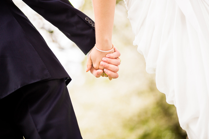 Close up of wedding couple holding hands / wundervisuals Bride and groom walking together and holding hands
