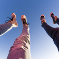 Young couple lifts their legs towards clear blue sky